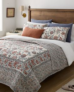 a bedroom with a bed covered in a floral comforter and matching pillow shampoos