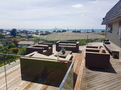 an outdoor deck with chairs and tables overlooking the ocean