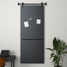 a black refrigerator freezer sitting on top of a wooden table next to a potted plant