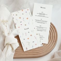 two menu cards sitting on top of a wooden tray next to a white cloth napkin