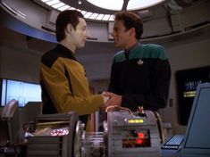 two men standing next to each other in front of a laptop computer and another man wearing a star trek uniform