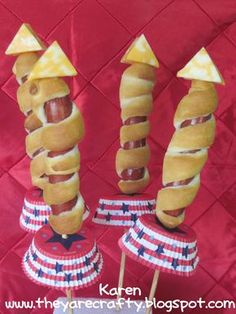 hot dogs wrapped in buns and topped with ketchup are displayed on sticks