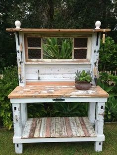 an old wooden bench with a potted plant on it and a mirror above the bench