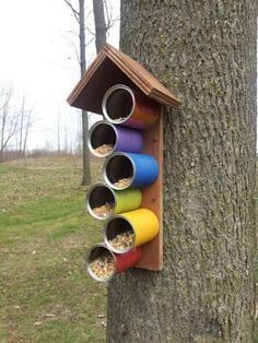 a bird house hanging on the side of a tree filled with birds feeders and food