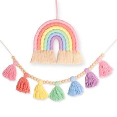 a rainbow decoration with tassels hanging from it's sides and a wooden beaded necklace