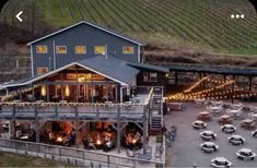 an aerial view of a restaurant with outdoor seating and lights on the patio, surrounded by vineyards