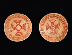 two red and white plates sitting on top of a black table next to each other