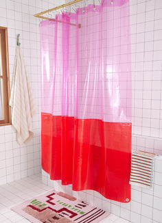 a pink and red shower curtain in a bathroom with white tile flooring on the walls