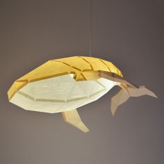 a light that is shaped like a fish hanging from the ceiling in front of a gray wall