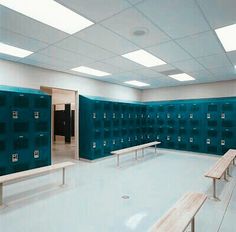 an empty locker room with benches in the middle and several doors on each side to separate rooms