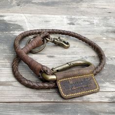 a brown leather dog leash with brass fittings and an engraved name tag on it