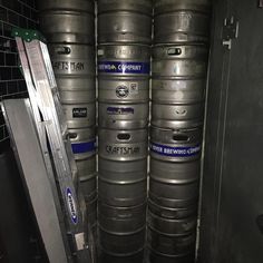 several large metal kegs stacked on top of each other in a room with black tile walls