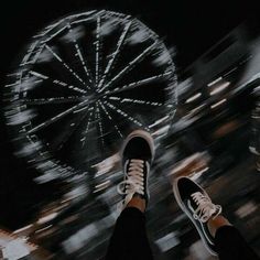 a person standing in front of a ferris wheel with their feet up on the ground