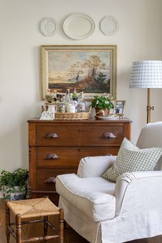 a living room filled with furniture and a painting on the wall over a chest of drawers