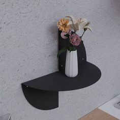 a vase with flowers is on the wall next to a shelf that's shaped like an arrow