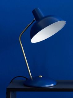 a desk lamp sitting on top of a wooden table next to a blue wall and floor