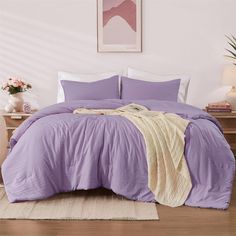 a bed with purple sheets and pillows in a room