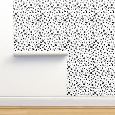 a white wall with black spots on it and a wooden floor in front of it