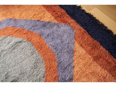 an orange, blue and grey rug on the floor