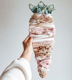 a person holding up a stack of cloths with flowers on top of them, in front of a white wall