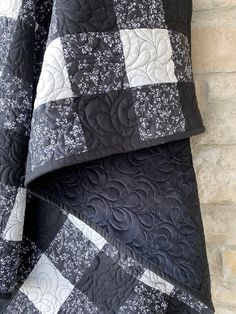 the black and white quilt is laying on top of the stone wall next to it