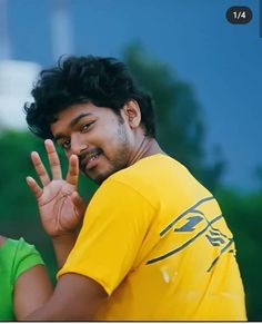 a man making the vulcan sign with his hand while wearing a yellow t - shirt