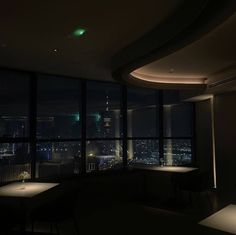 a dimly lit room with large windows overlooking the city