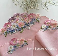 two pink napkins with embroidered flowers on them