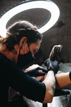 a woman is getting her tattoo done by someone else in a black shirt and gloves