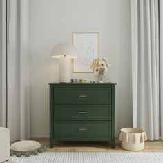 a green dresser with flowers on top in front of a white curtained room window