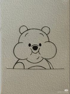 a drawing of a teddy bear on a white wall with black outline and the shape of a face