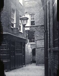 an old black and white photo of a street light on the side of a building