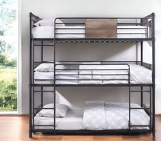 a metal bunk bed with white sheets and pillows on the bottom level, in front of a window