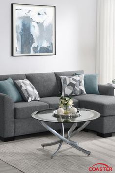 a living room with a gray couch and coffee table in front of a painting on the wall