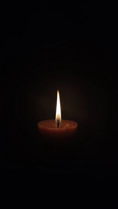 a lit candle in the dark on a black background