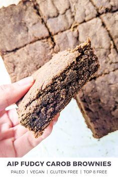 a hand holding a piece of brownie in it's left hand next to another one