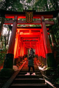 a woman is standing in front of an archway with red lights at the end and stairs leading up to it