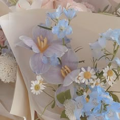 a bunch of flowers that are on top of some wrapping paper with blue and white flowers