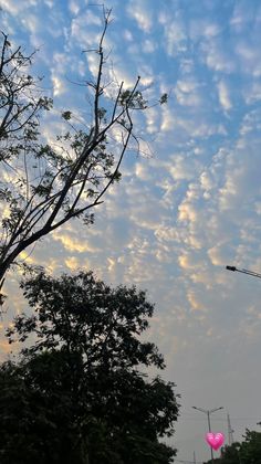 the sky is filled with clouds and pink heart shaped balloons