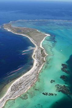 an aerial view of the ocean and landforms from above, with clear blue water