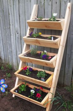 a wooden planter filled with flowers next to a fence and flower potted plants