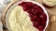 a bowl filled with cream and cranberry sauce on top of a wooden table