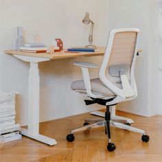 an office chair sitting in front of a desk with books on it and a lamp next to it