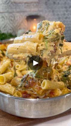 a pan filled with pasta and broccoli being lifted from the pot by a wooden spoon