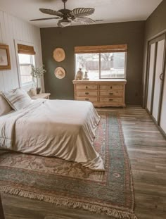 a bedroom with a bed, dresser and ceiling fan in the middle of the room