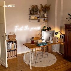 a desk with a computer on top of it in front of a wall mounted shelf