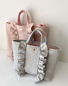 three purses sitting next to each other on top of a white table with pink handles