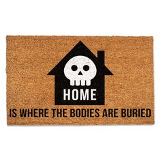 a door mat that says home is where the bodies are buried with a skull on it