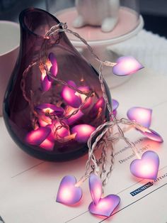 a purple vase sitting on top of a table next to a cup