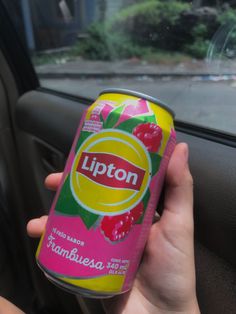 a person is holding up a can of lipton